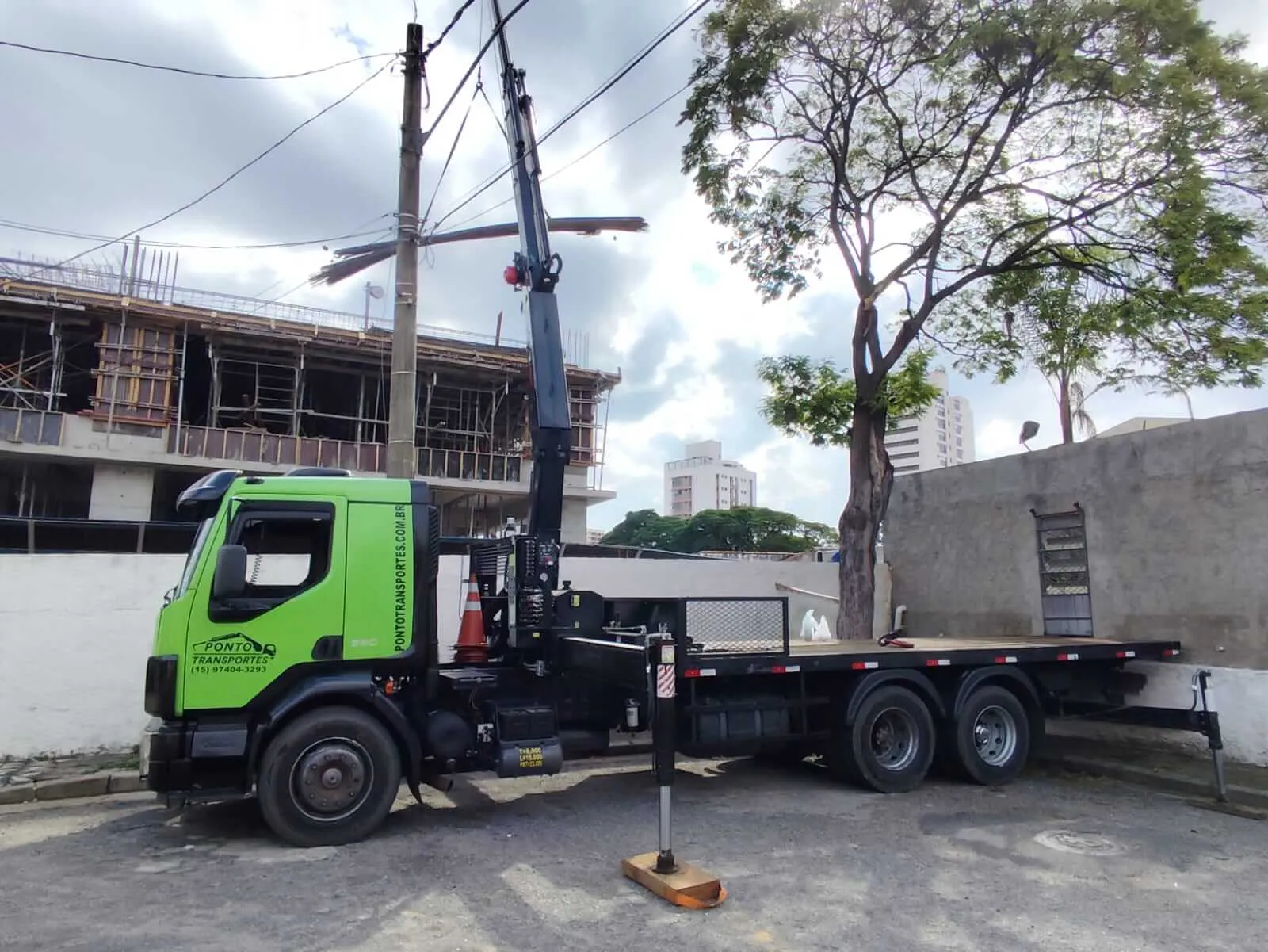 Caminhão munck com lança erguida em obra urbana