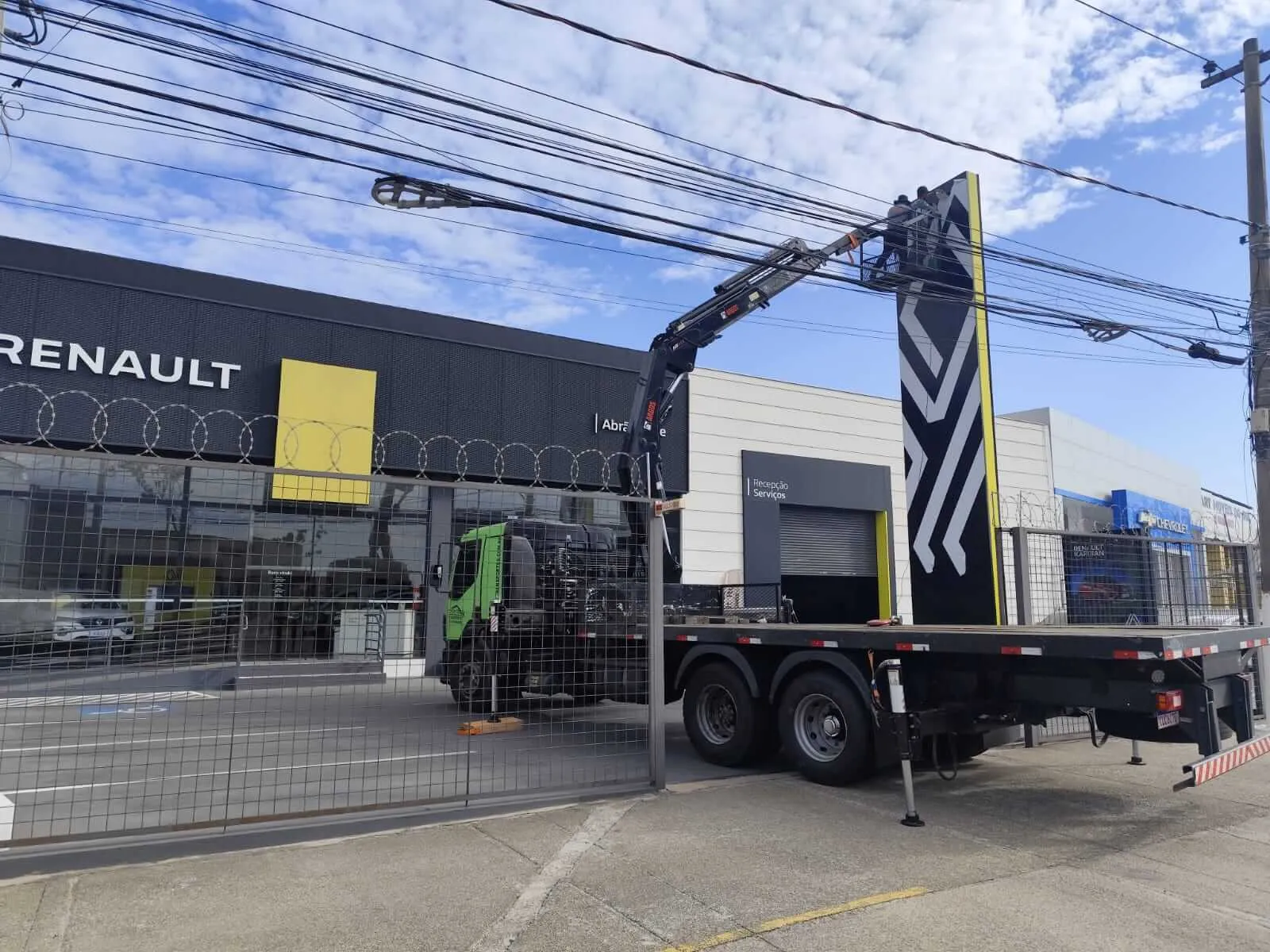 Caminhão munck instalando totem em concessionária Renault