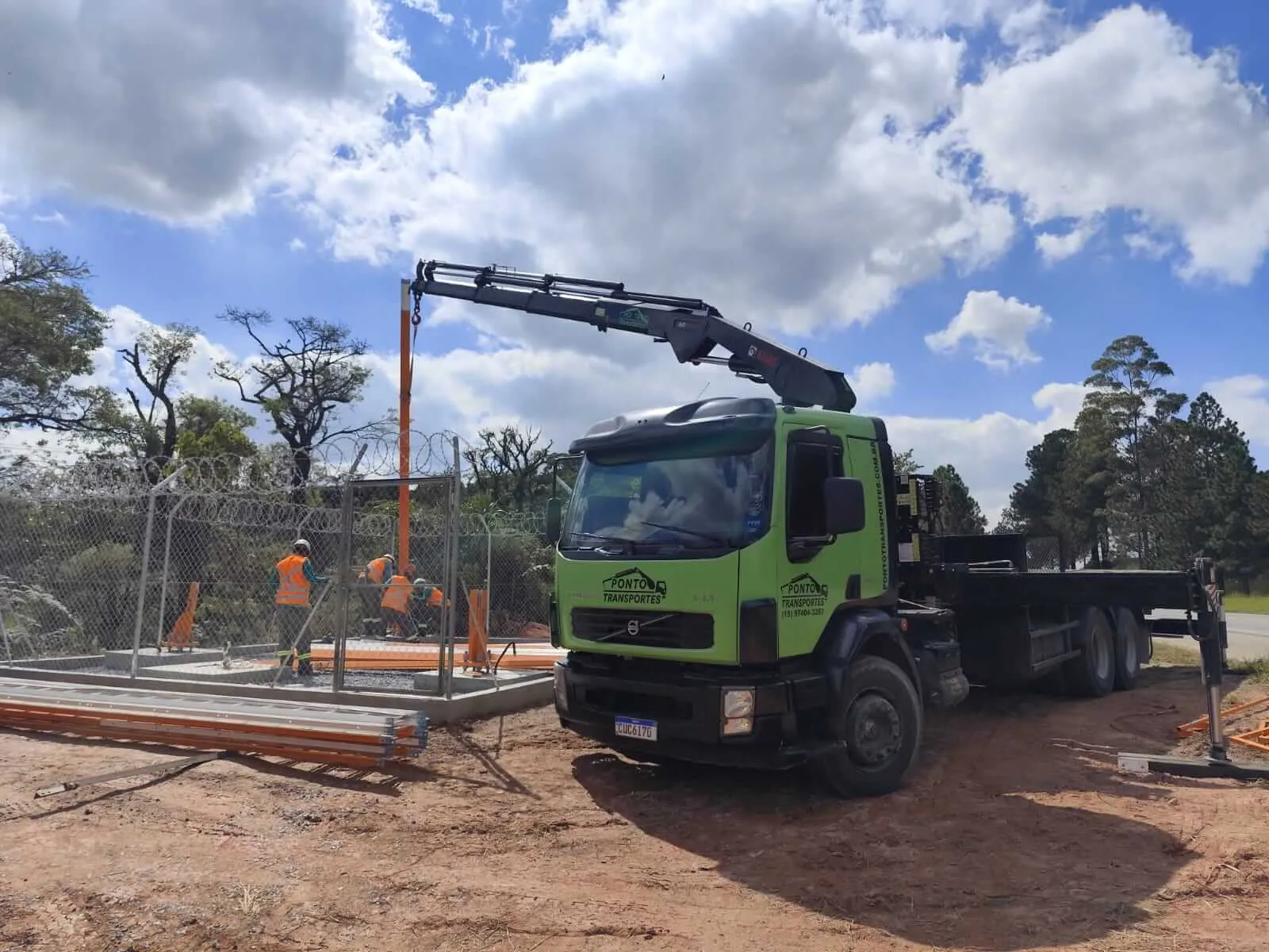 Caminhão munck içando estrutura metálica em terreno de obra